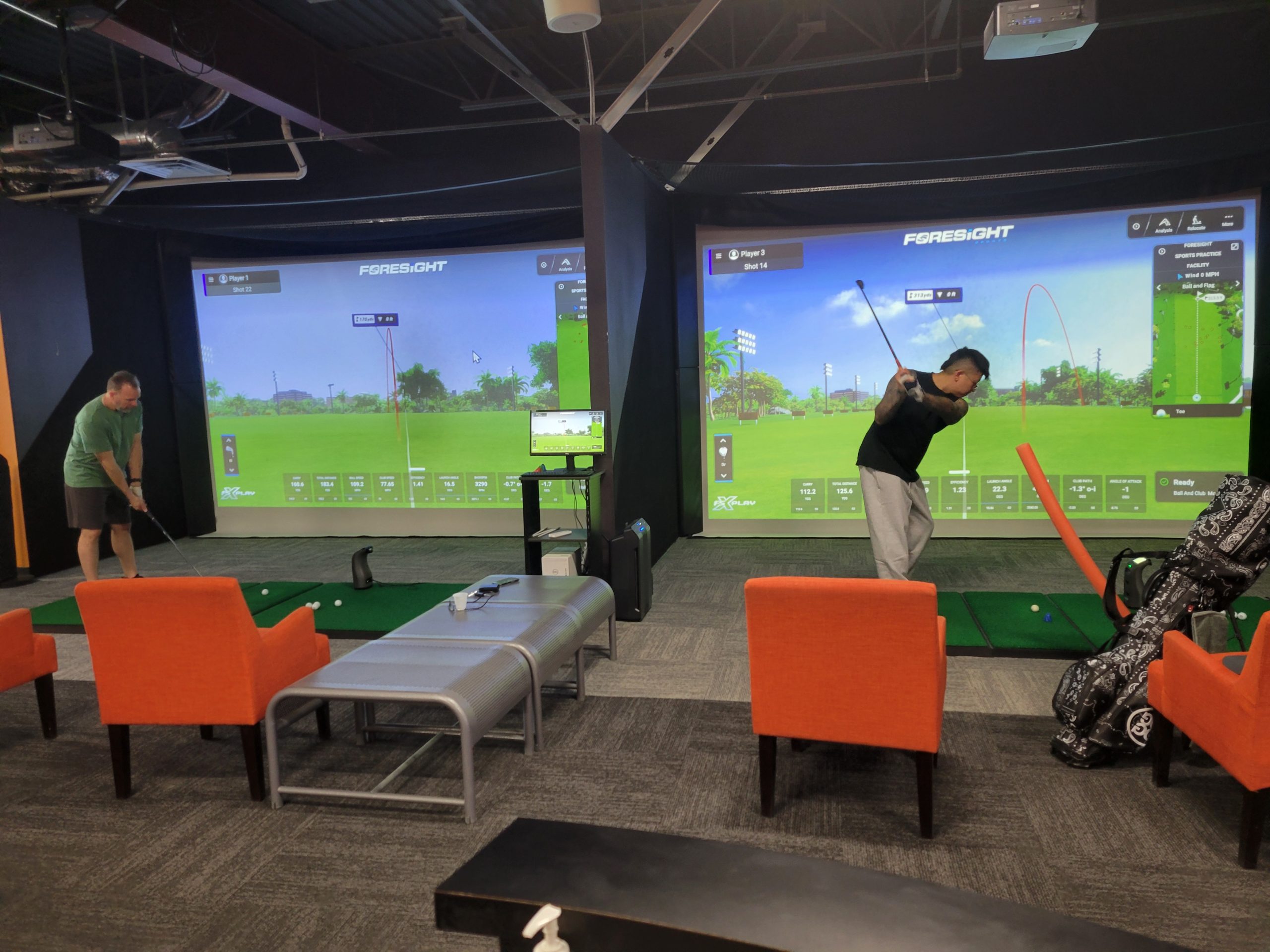Golfers practicing in adjacent indoor simulator bays at RoboGolfPro Las Vegas